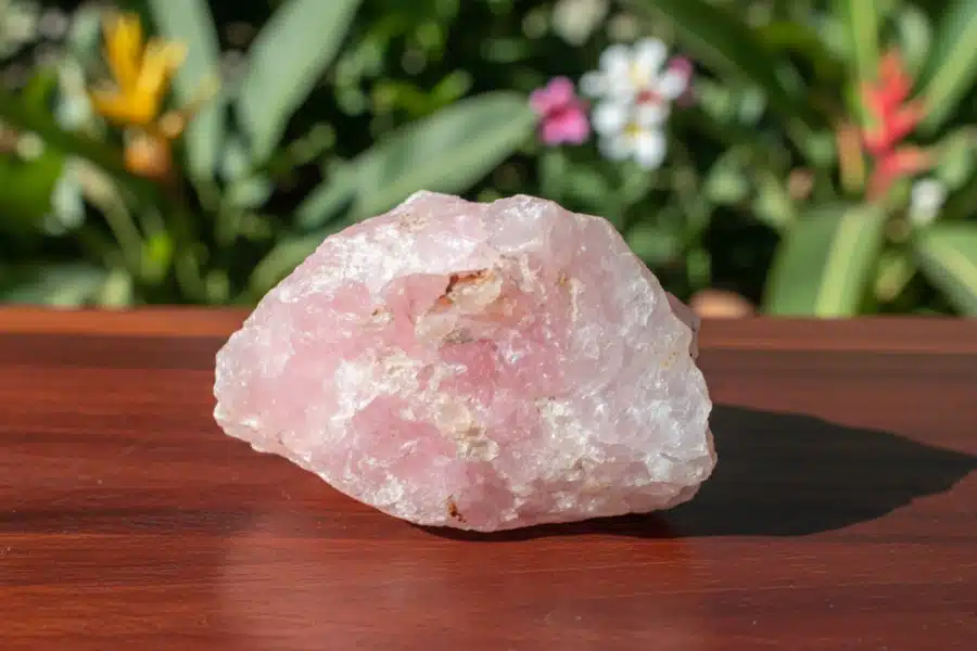 bloc de quartz rose posé sur une table en bois exotique bloc de quartz rose posé sur une table en bois exotique